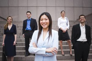 Young Professional Woman standing with team smiling